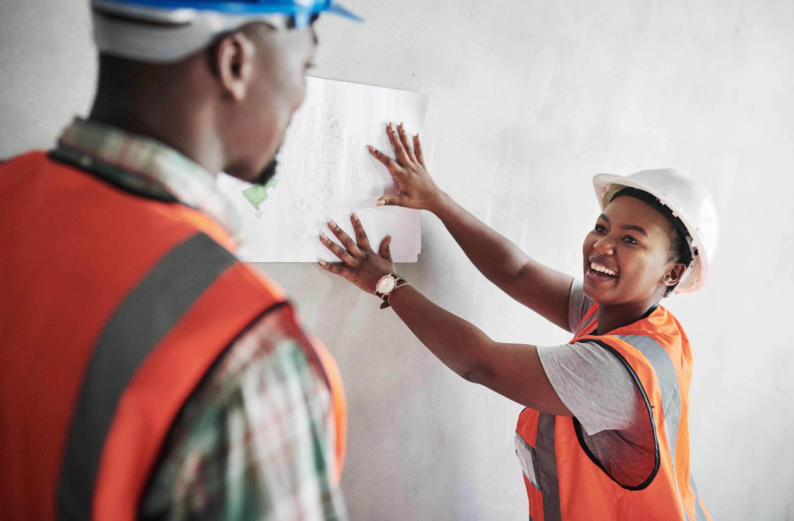 Shot of a young man and woman going over building plans at a construction site.