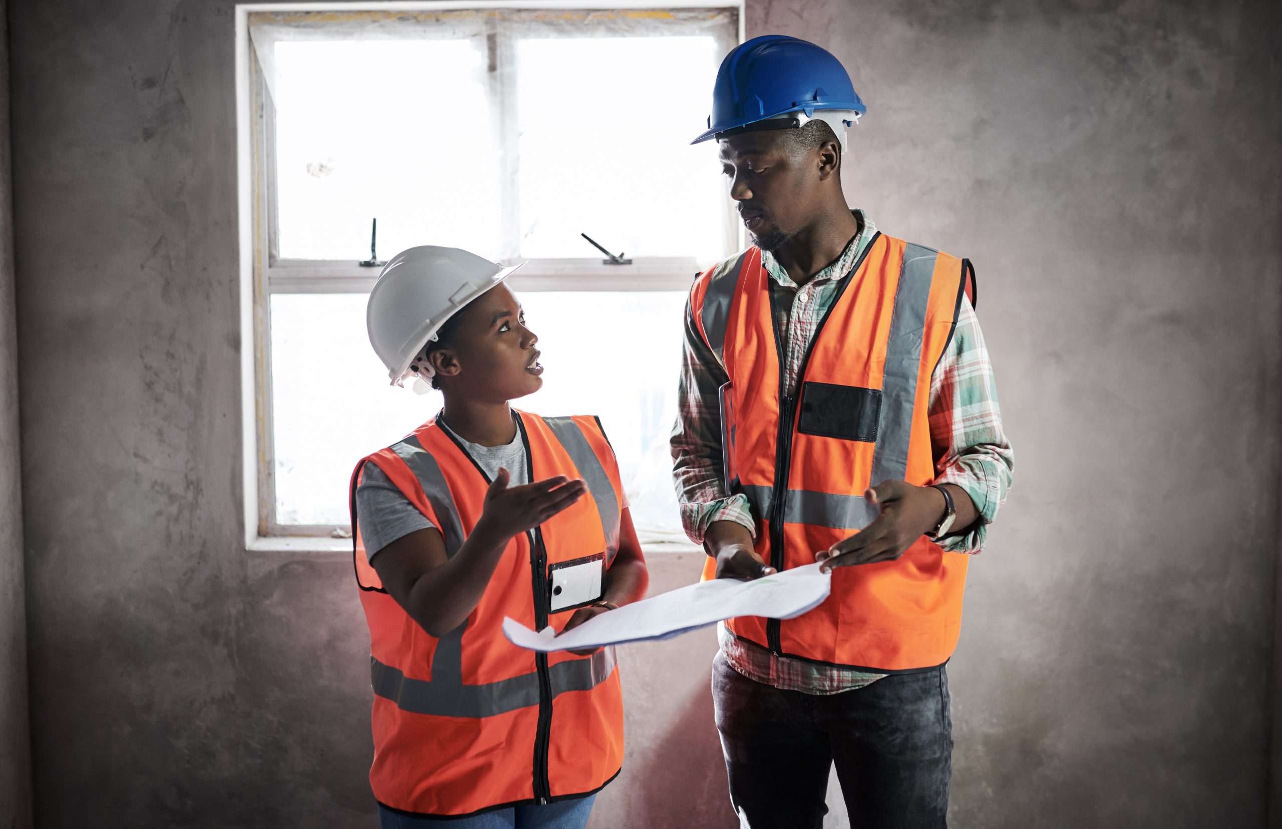 Shot of a young man and woman going over building plans at a construction site.